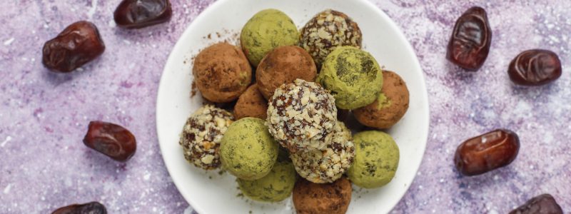 Homemade healthy vegan raw energy truffle balls with dates and walnuts,matcha powder,cocoa powder on light background
